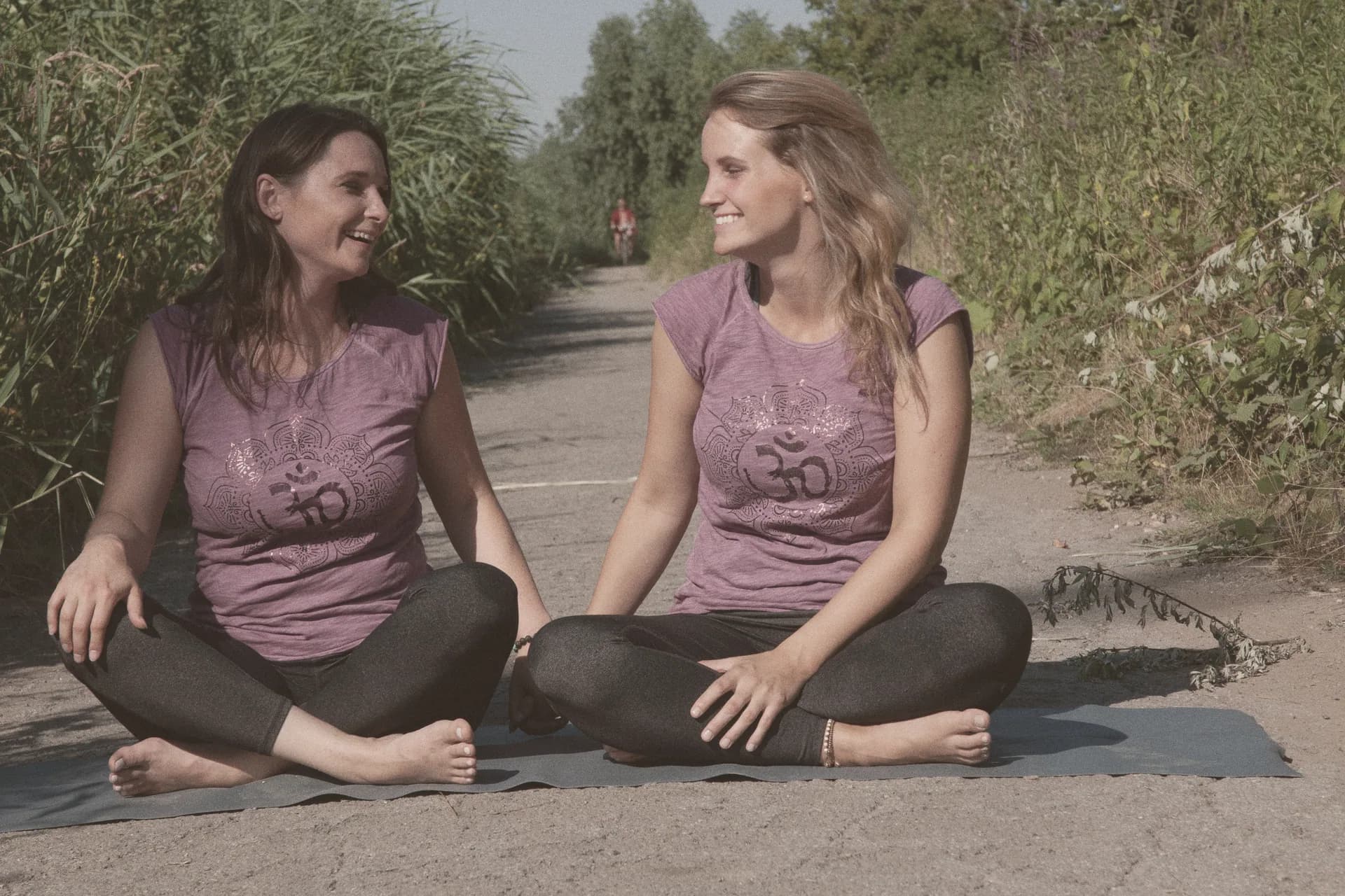 Jessica und Viktoria sitzen lachend auf einer Yogamatte